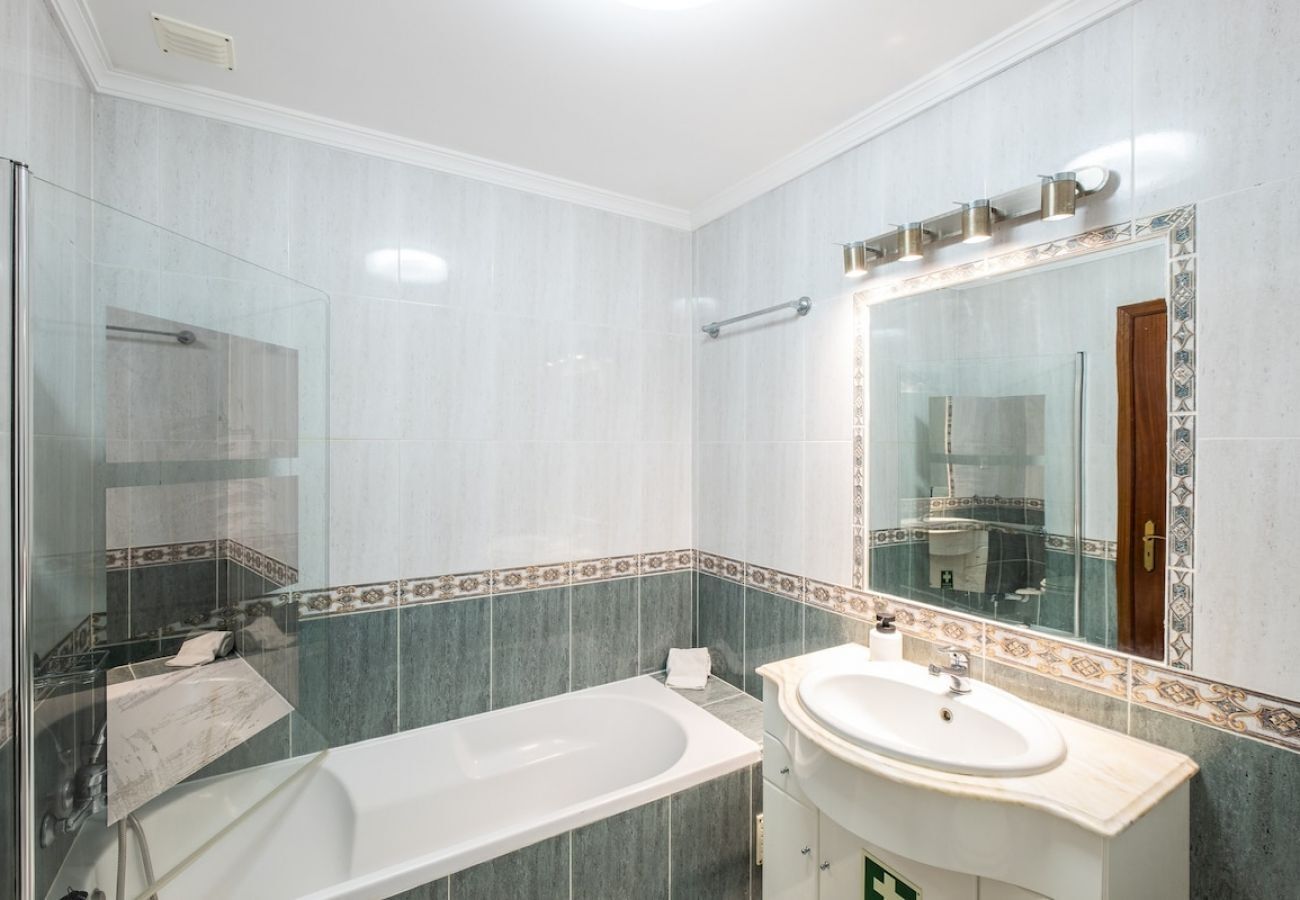 A bathroom with a glass-enclosed shower, a bathtub, and a sink with a mirror above it.