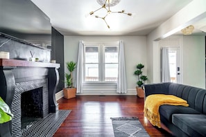 A living room with a fireplace, a sofa, and a large window with curtains.