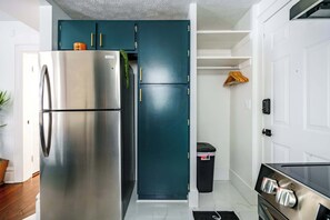 Una cocina con un refrigerador de acero inoxidable, un gabinete color turquesa y una puerta blanca.