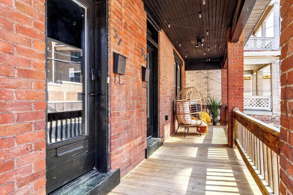 A covered outdoor corridor with brick walls, wooden flooring, and a railing on one side.