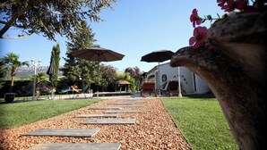 A garden pathway leading to a building with outdoor seating and umbrellas. - Luxurious Villa with Heated Pool and Jacuzzi in Scenic Nans-les-Pins (Saint-Rémy-de-Provence)