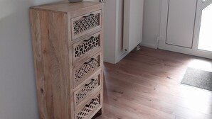 Een houten kast met laden, een ronde spiegel en een vaas met bloemen erop.