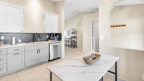 Une cuisine moderne avec des meubles gris, un plan de travail en marbre et un lave-vaisselle encastré.