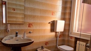A bathroom with a sink, toilet, and bathtub, featuring tiled walls and a skylight. - Hotel Tito (Mestre)