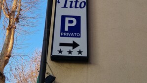 A vertical sign for Hotel Tito with a private parking symbol and directional arrows. - Hotel Tito (Mestre)