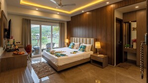 A modern hotel room with a large bed, a desk, and a view of the outdoors. - The Eden Inn By The Saga Stays (Anjuna)