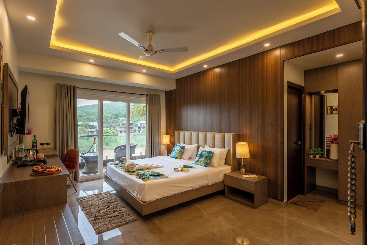 A modern hotel room with a large bed, a desk, and a view of the outdoors.