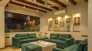 A modern living room with green sofas, a glass coffee table, and artwork on the walls. - The Eden Inn By The Saga Stays (Anjuna)