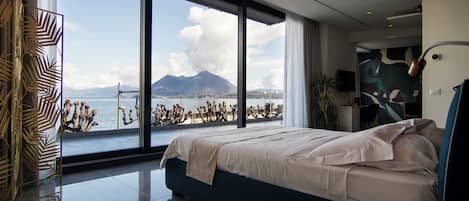 Un dormitorio moderno con una cama grande, vistas al mar y a las montañas, y una decoración minimalista.