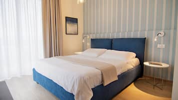 Ein modernes Schlafzimmer mit einem großen Bett, einem Nachttisch und einer wandmontierten Lampe.