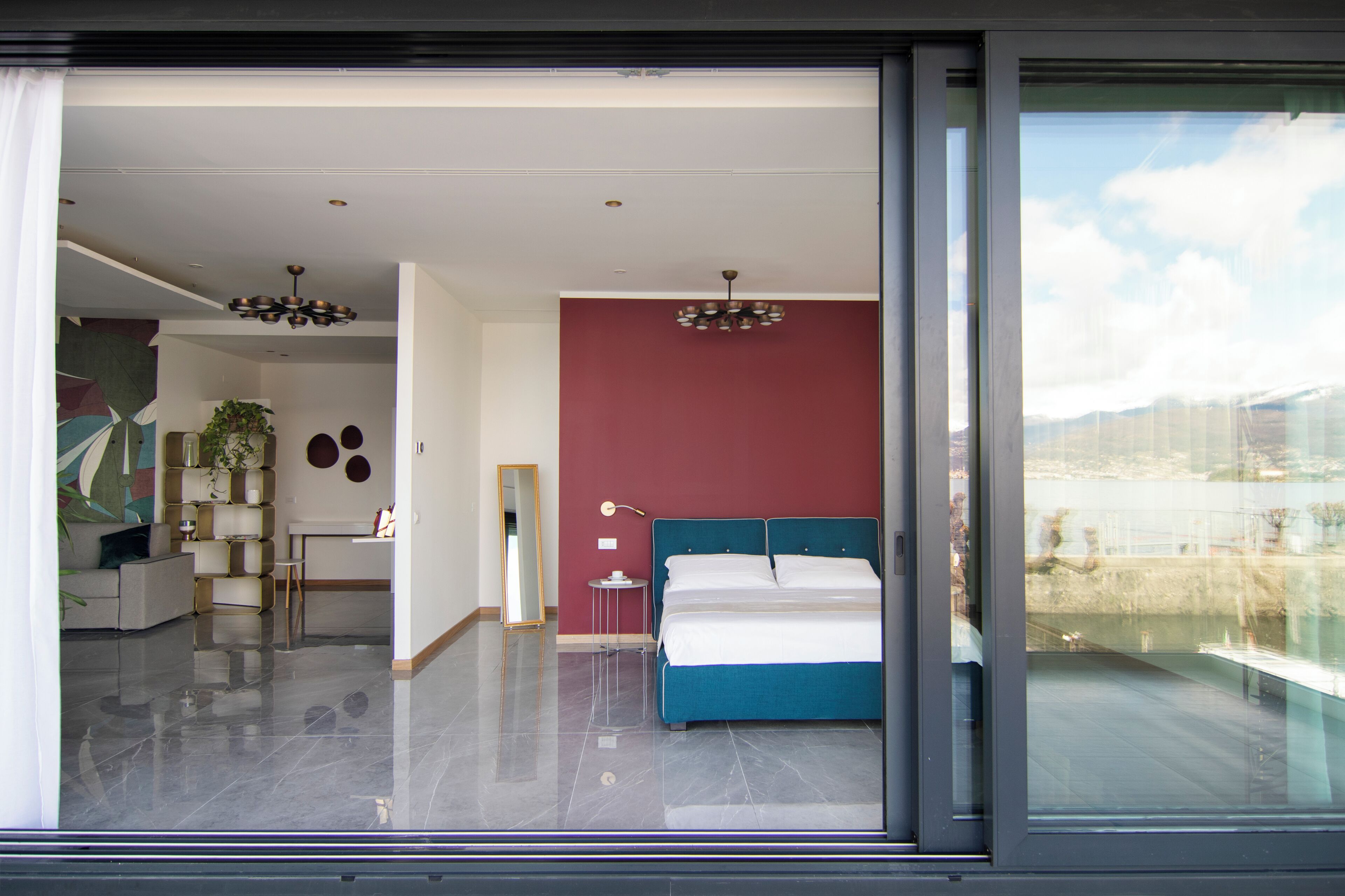 Een moderne slaapkamer met een groot bed, een rode accentmuur en uitzicht op de omgeving.