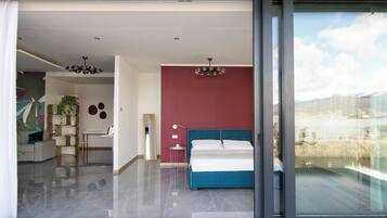 Een moderne slaapkamer met een groot bed, een rode accentmuur en uitzicht op de omgeving.
