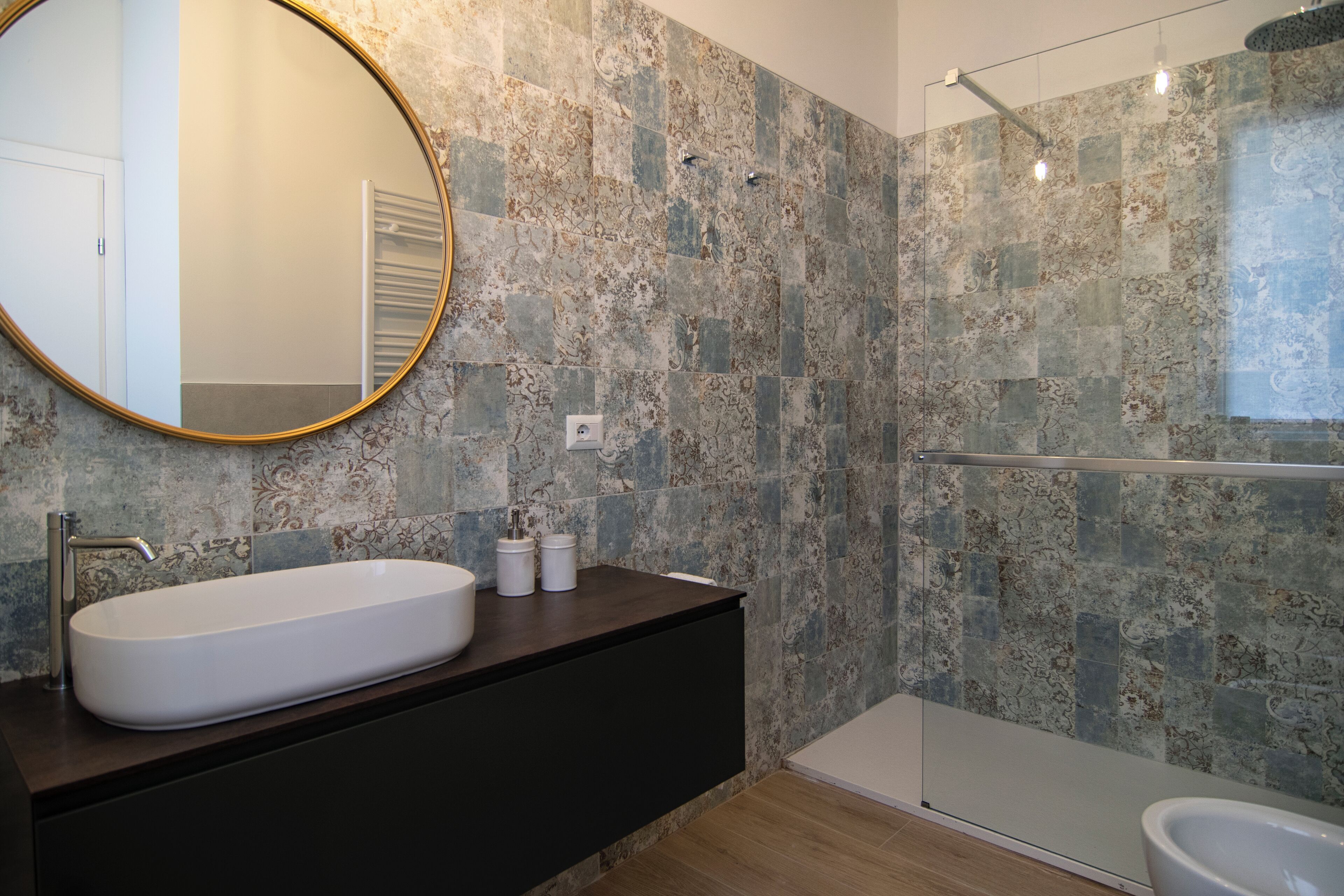 Un baño moderno con una bañera independiente, un lavabo ovalado grande y un espejo redondo.