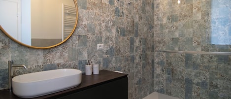 A modern bathroom with a freestanding bathtub, a large oval sink, and a round mirror.