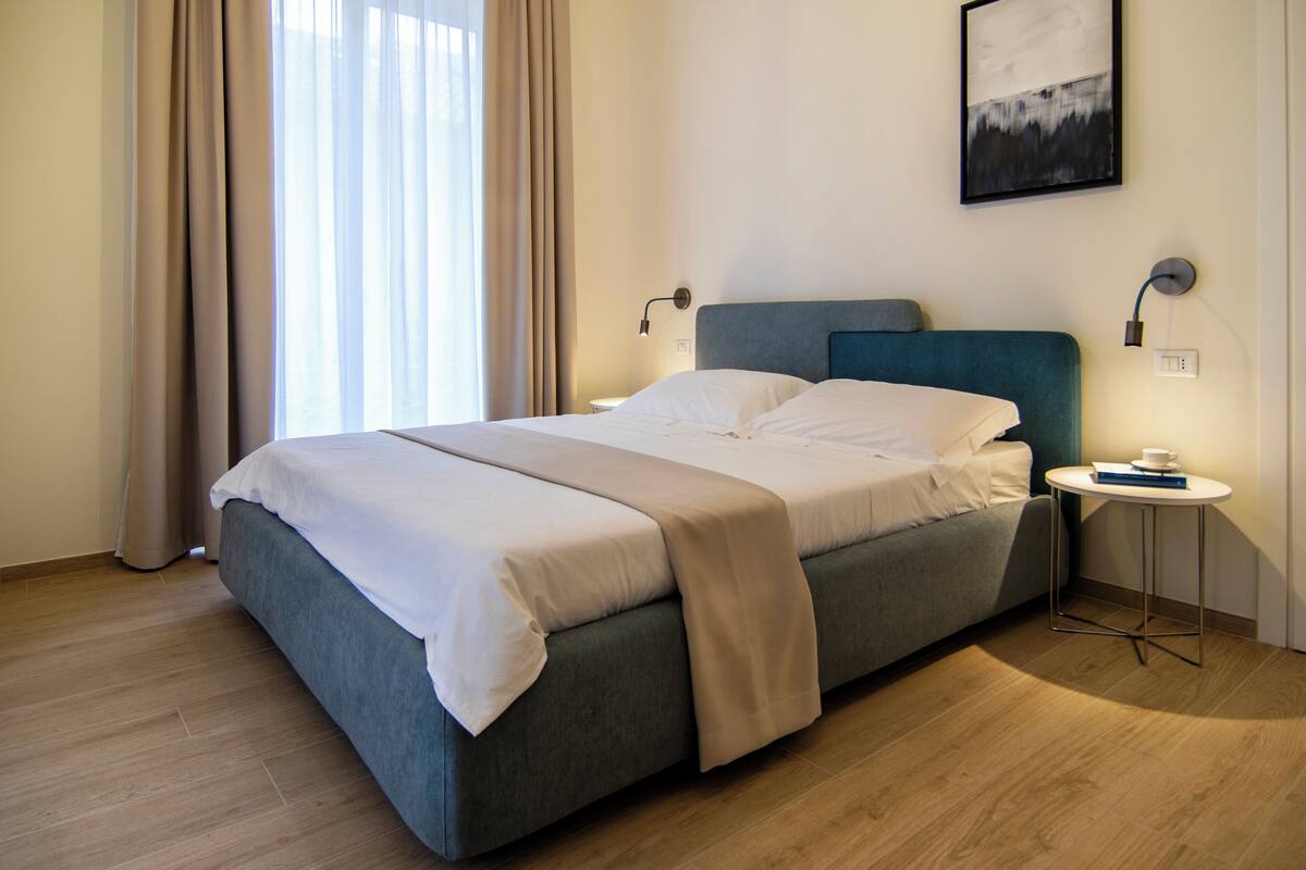 Ein modernes Hotelzimmer mit Bett, Nachttisch und einem Wandbild.