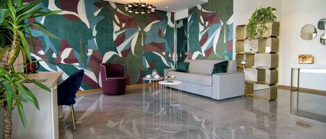 Een moderne woonkamer met een grote abstracte muurschildering, een bank, een salontafel en een plant.