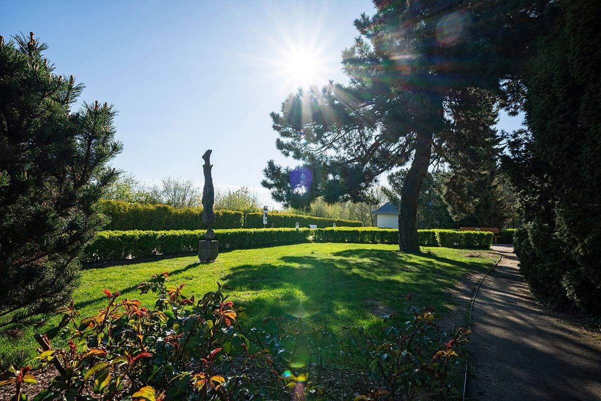 Um jardim bem cuidado, com um caminho bem definido, sebes podadas e uma estátua no centro.