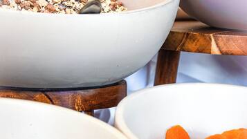 Una mesa con cuatro recipientes blancos que contienen distintos tipos de comida.