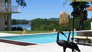 A poolside area with a swan-shaped light fixture, a wicker birdcage light, and a black lantern.