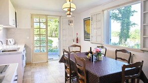 A kitchen with a dining area, a large window, and a door leading to a garden.