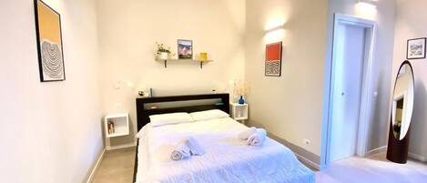 A modern bedroom with a large bed, bedside tables, and wall-mounted shelves.