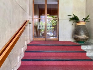 Eine Treppe mit rotem Teppich, die zu einer Tür mit Glasscheiben führt.