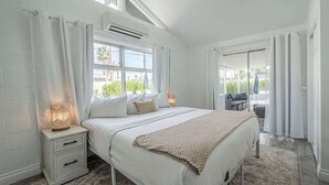 A bedroom with a large bed, a nightstand with a lamp, and a view of the outdoors through a window. - Scottsdale Lux Oasis, Pool Hot Tub Sleeps 12! (Scottsdale)