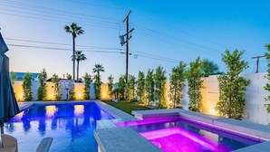 A swimming pool with a separate hot tub area, surrounded by a well-maintained garden and a white wall. - Scottsdale Lux Oasis, Pool Hot Tub Sleeps 12! (Scottsdale)