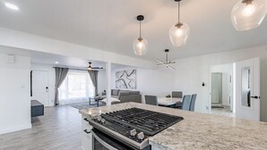 A modern kitchen with a built-in stove and oven, a dining area with a table and chairs, and pendant lighting. - Scottsdale Lux Oasis, Pool Hot Tub Sleeps 12! (Scottsdale)