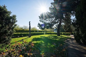 A well-maintained garden with a clear pathway, neatly trimmed hedges, and a variety of trees. - Strandhotel Luise von Preussen (Zinnowitz)