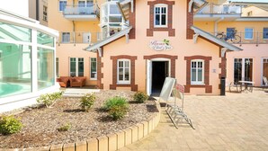 A multi-story building with balconies, a central entrance, and a small outdoor seating area. - Strandhotel Luise von Preussen (Zinnowitz)