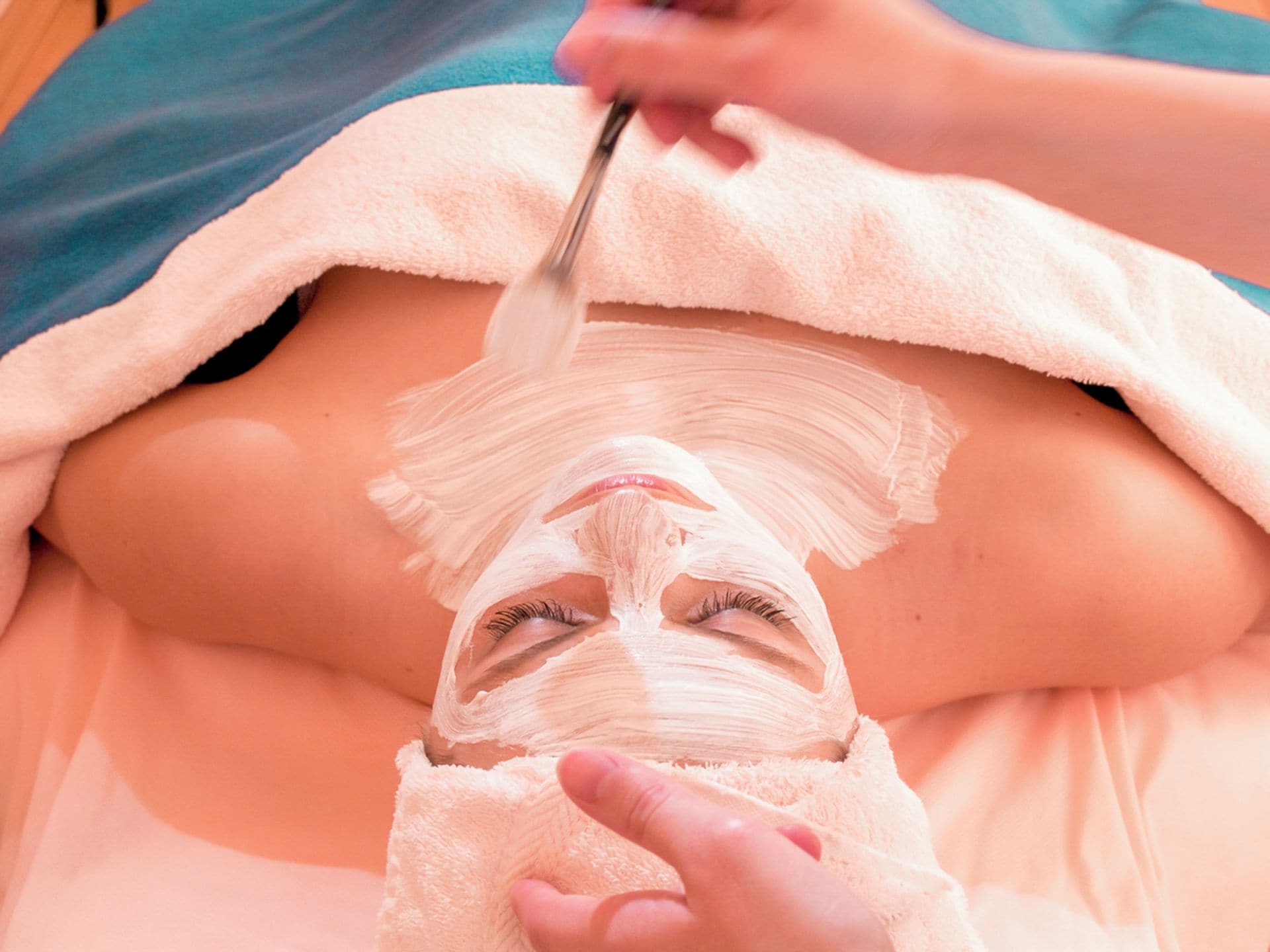 Una persona recibiendo un tratamiento facial con una toalla cubriendo su torso.