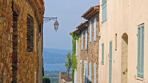 Une rue étroite bordée d’immeubles en pierre, un lampadaire et une vue sur la mer.