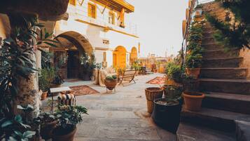 Un patio con escalones de piedra, plantas en macetas y un edificio rústico con arcos.