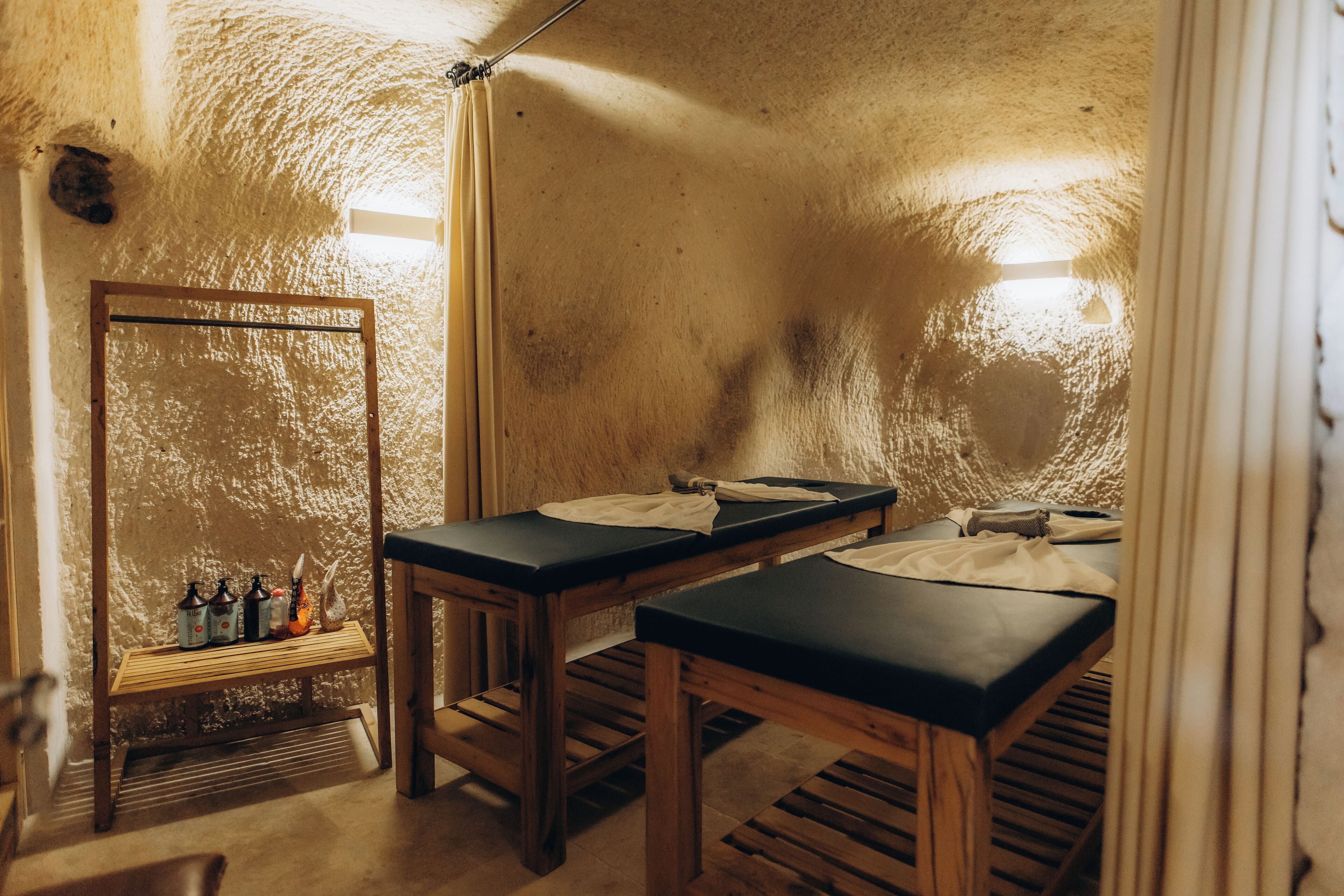 A rustic room with wooden benches, a mirror, and a shelf with bottles.