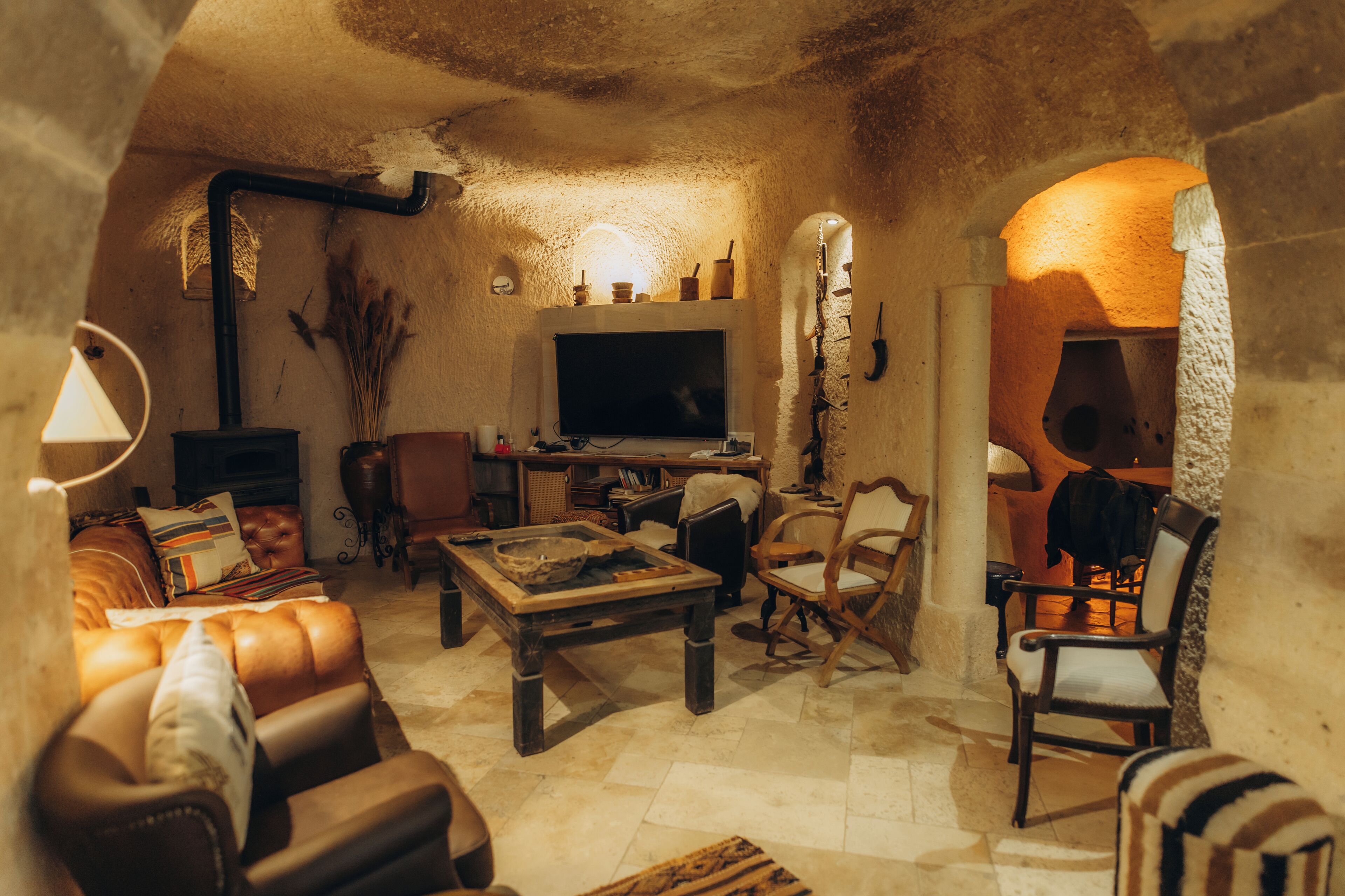 Un salon chaleureux et rustique, doté d’une cheminée, d’un canapé en cuir, d’une table basse en bois et d’un téléviseur.