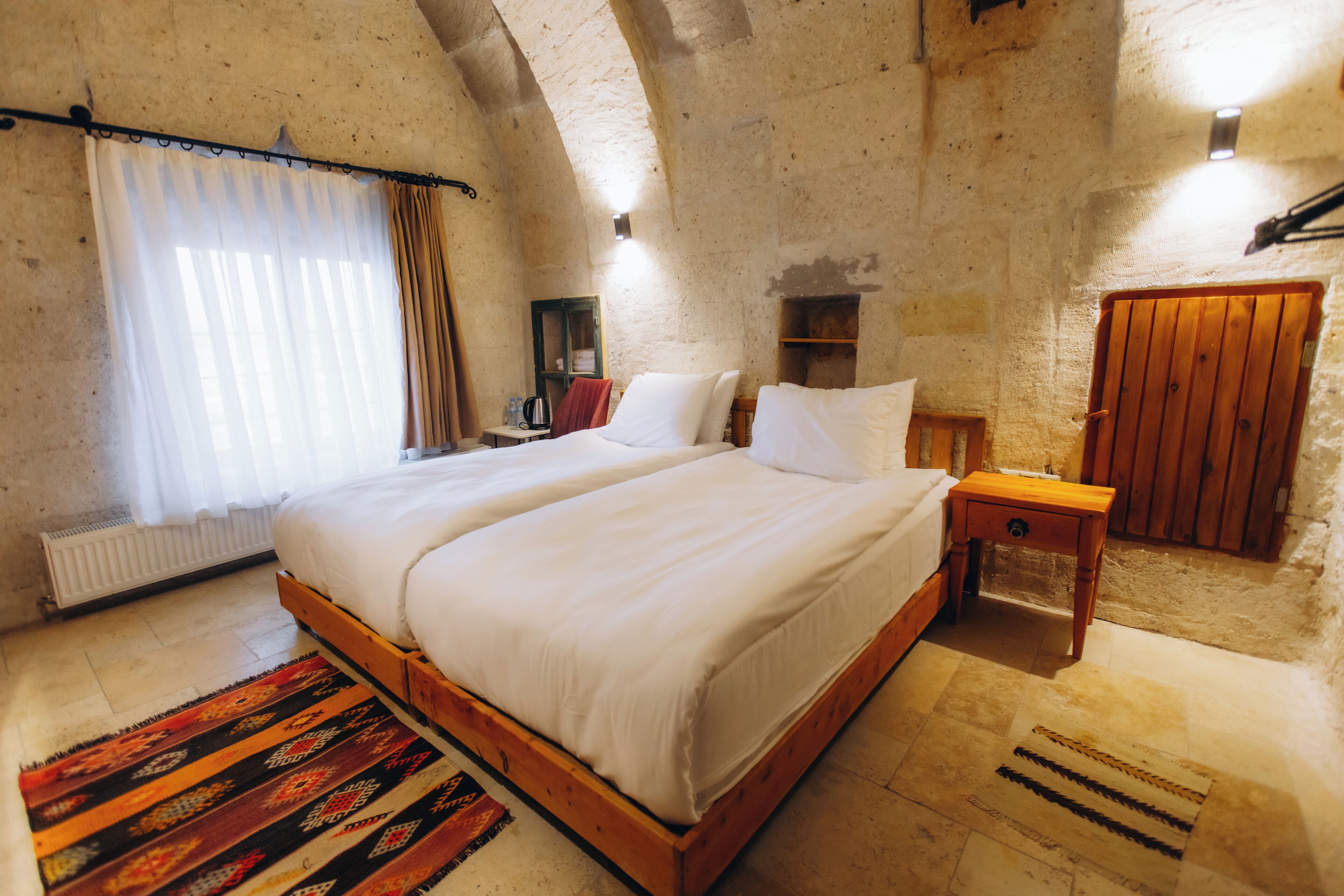 A bedroom with a large bed, a wooden nightstand, a wardrobe, and a radiator.