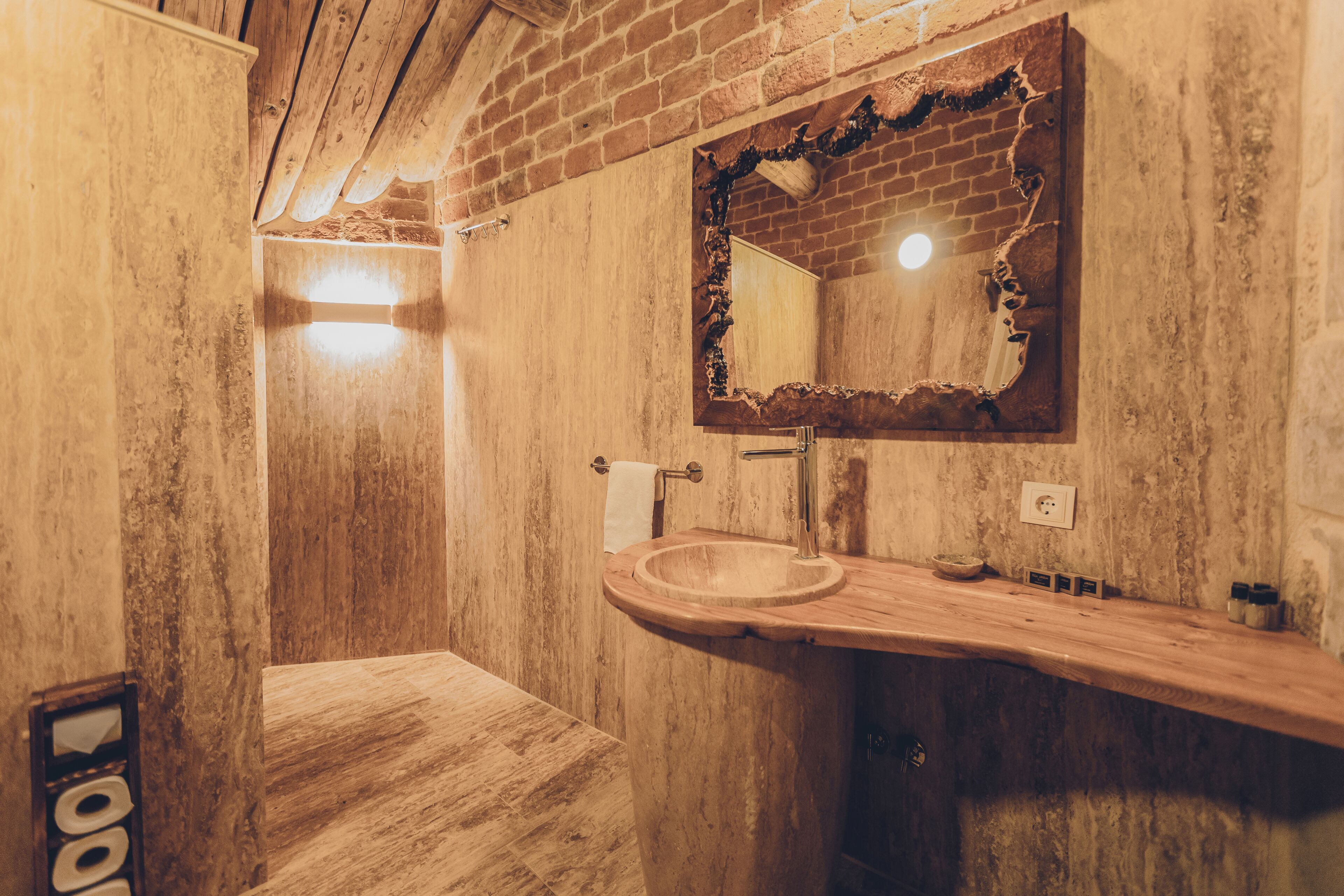 A rustic bathroom with a wooden vanity, a sink, and a mirror with a brick pattern.
