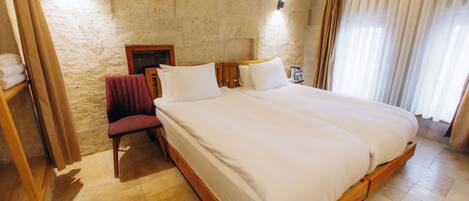 A bedroom with a large bed, a chair, a nightstand, and a wall-mounted lamp.