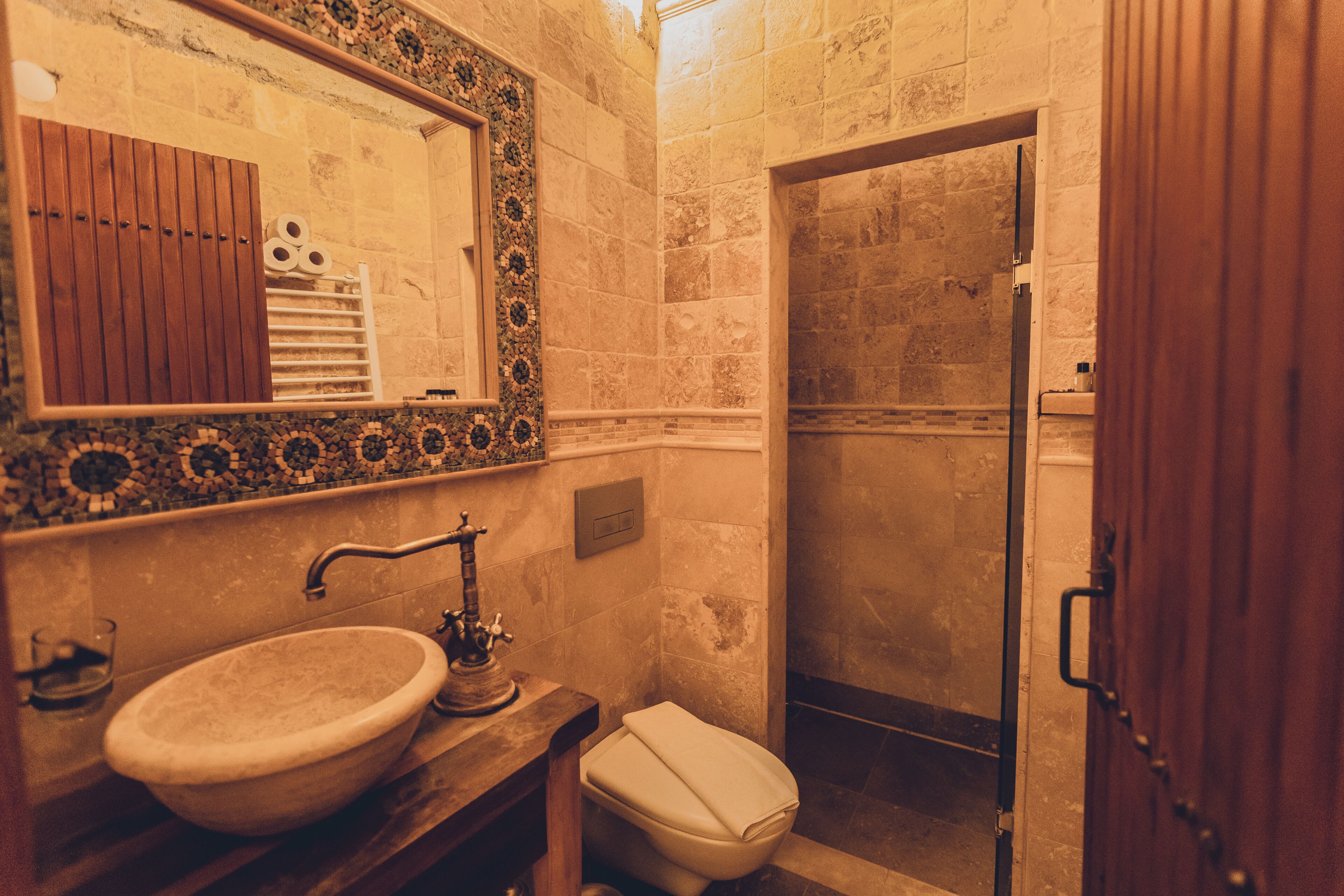 A bathroom with a sink, mirror, toilet, and shower.