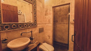 A bathroom with a sink, mirror, toilet, and shower.