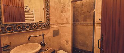 A bathroom with a sink, mirror, toilet, and shower.