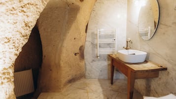 A bathroom with a marble sink, a wooden vanity, a mirror, and a towel rack.