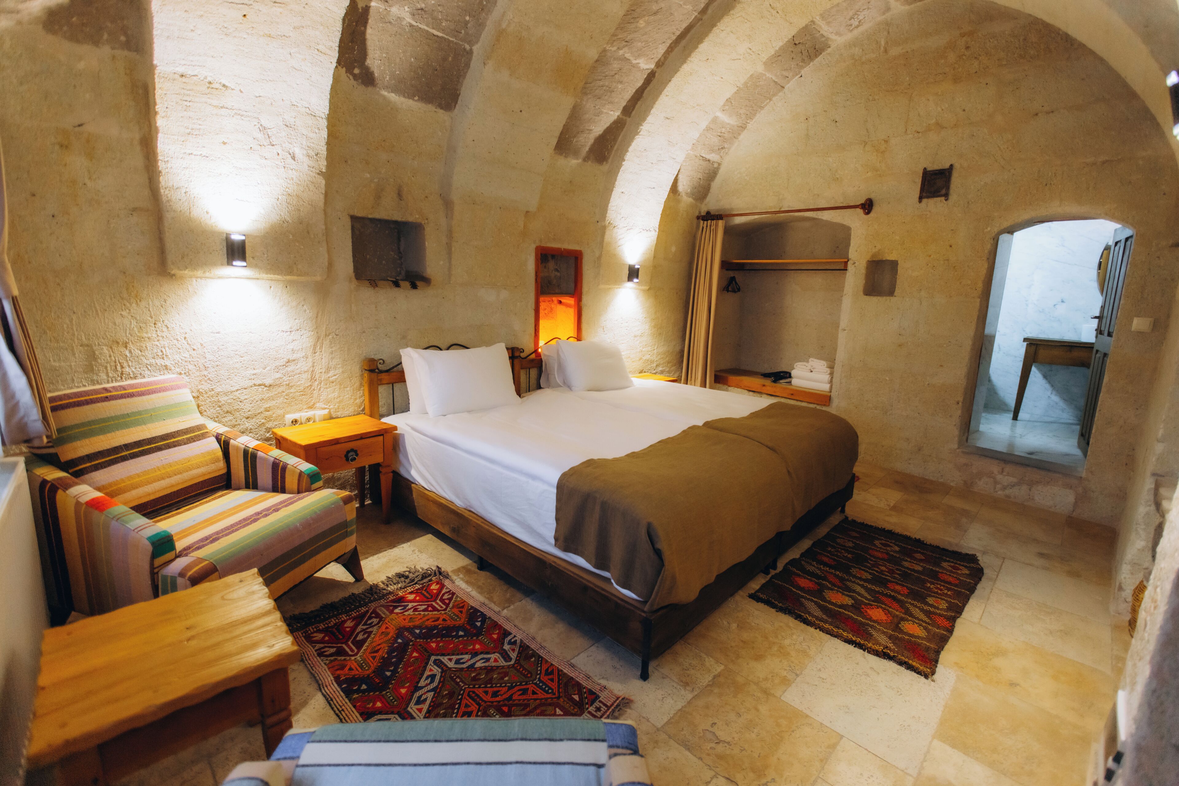 A cozy room with a bed, a chair, a nightstand, and a small table.