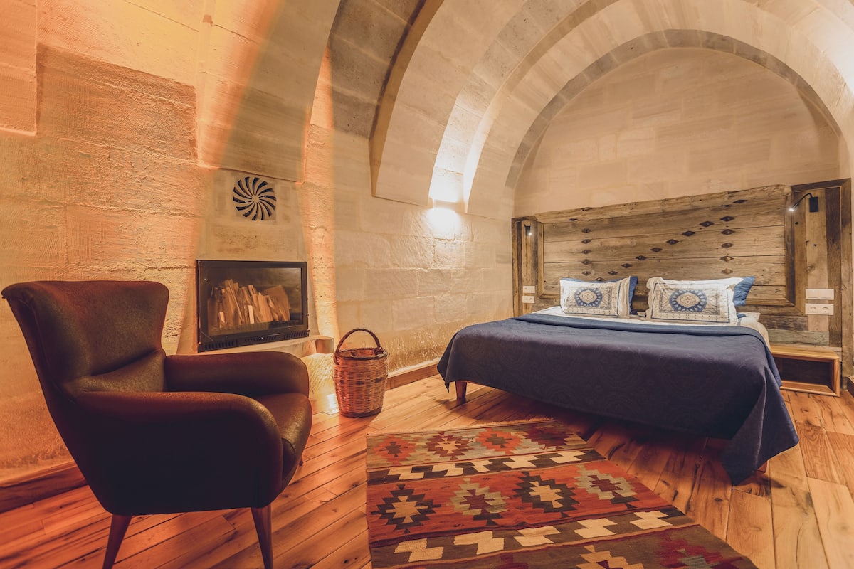 A cozy bedroom with a wooden bed, a dark armchair, and a patterned rug.