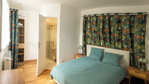 Un dormitorio con cama, mesita de noche de madera, armario y baño con ducha.