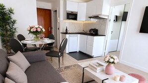 A modern living room with a grey sofa, a white coffee table, and a dining area with a table and chairs. - L'appartement Bouquet  (Paris)