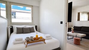 A bedroom with a bed, bedside table, and a tray with breakfast items. - L'appartement Bouquet  (Paris)