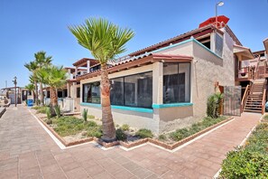 A modern building with a large window, a palm tree, and a brick pathway. - Super Beachfront Condo Ground Level on Sandy Beach (Puerto Peñasco)
