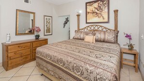 Un dormitorio con una cama grande, cómoda de madera y mesita de noche.